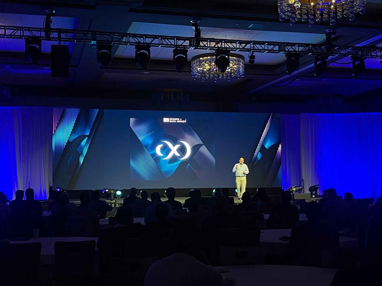 Delphix keynote on stage at DevOps and Data Impact, the X mark lit on the big screen